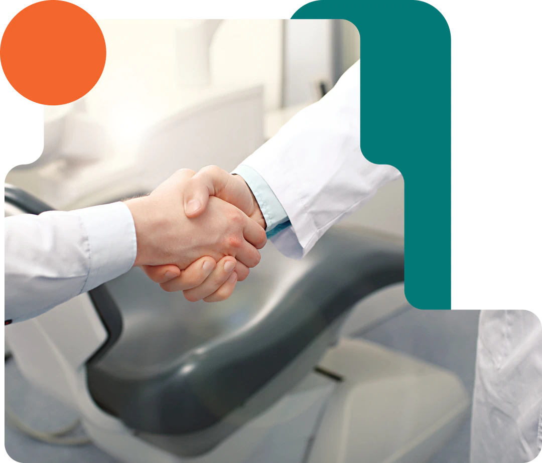 Desktop_About_Us_Why_Longview Two people in white coats shake hands in front of a dental chair, with geometric design elements overlaying the image.